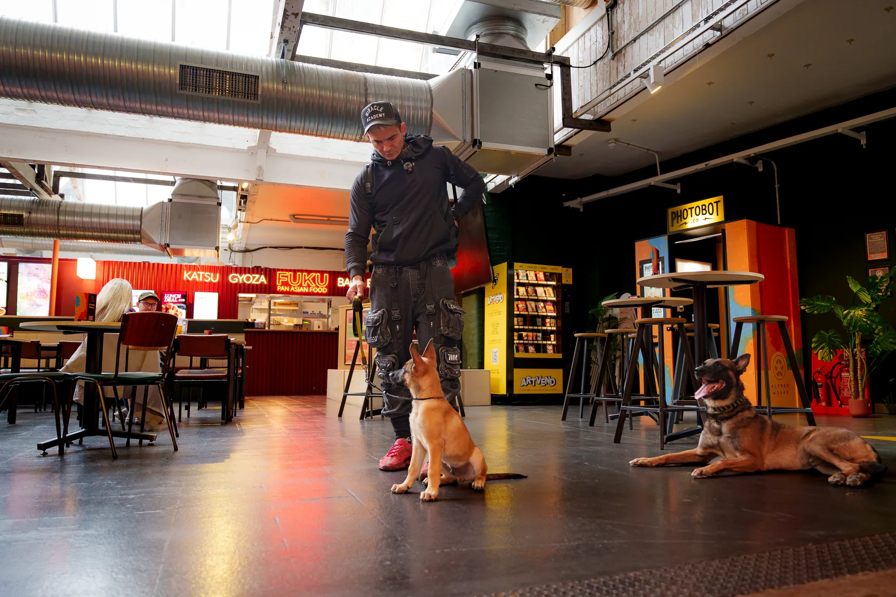 Andrejus training a dog indoors in an open public courtyard