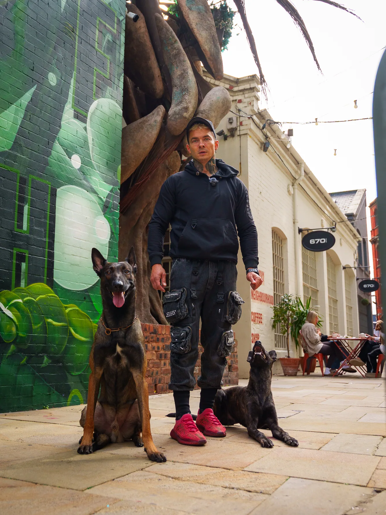Andrejus and two working dogs posing in an urban pedestrian area