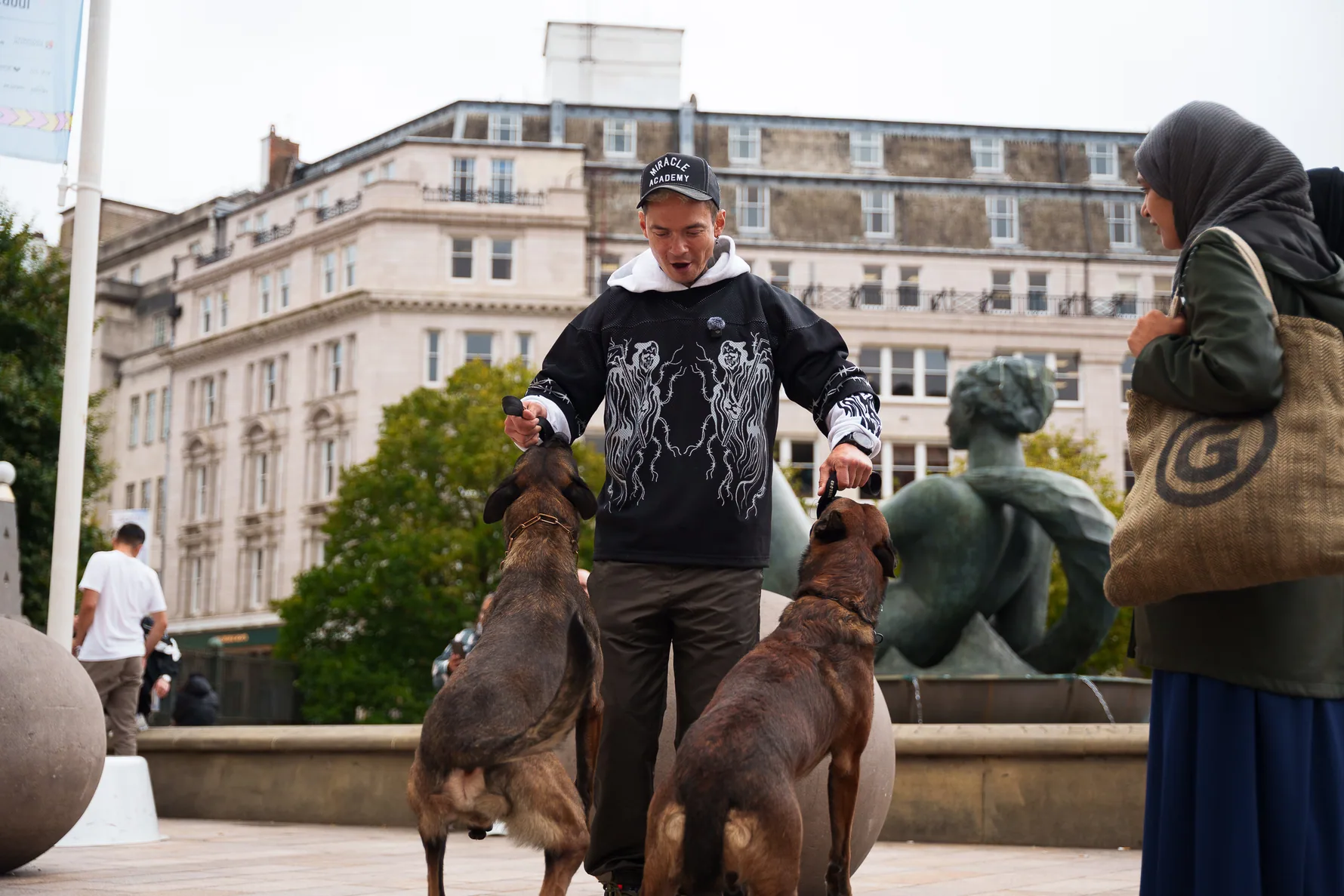 Focused working dogs beside Andrejus in an open urban square