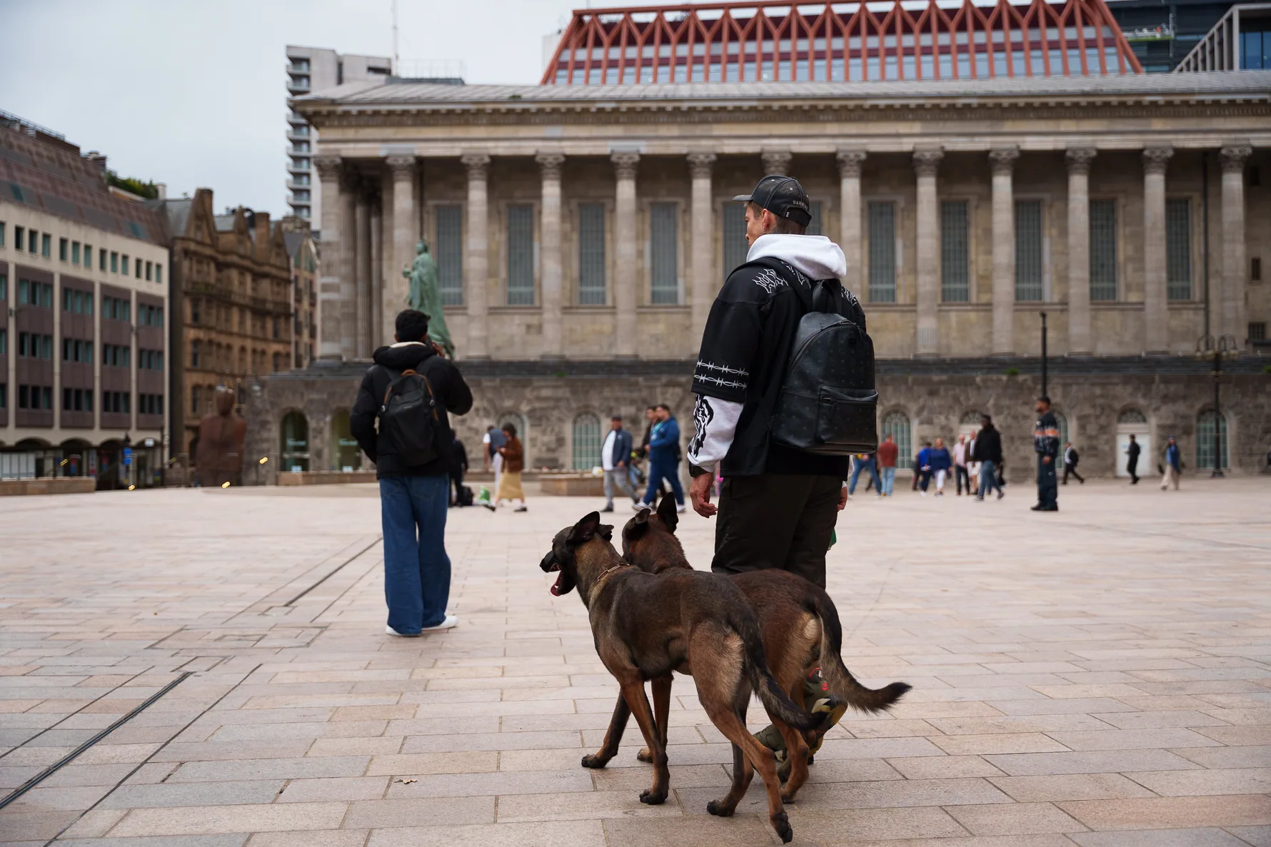 Andrejus and two dogs practising lead walking beside a public building