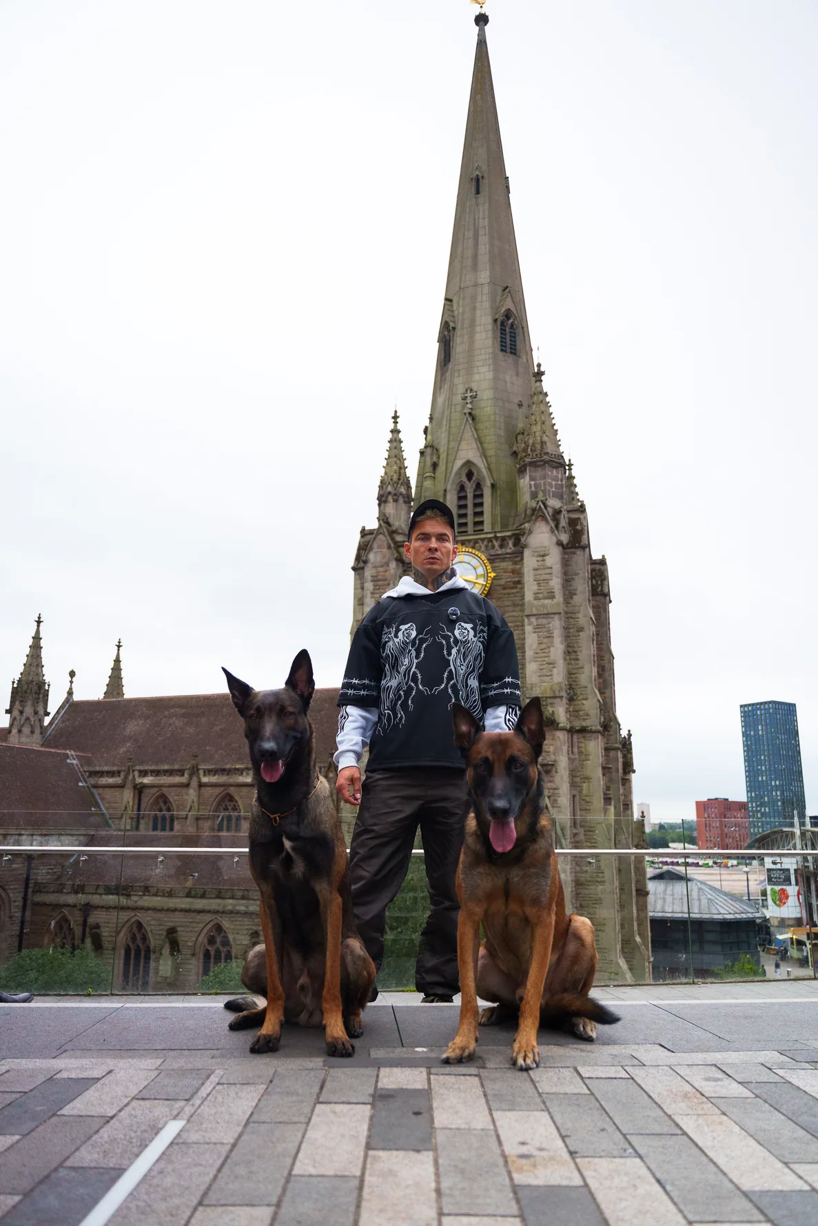 Two working dogs sitting calmly with Andrejus near a city church