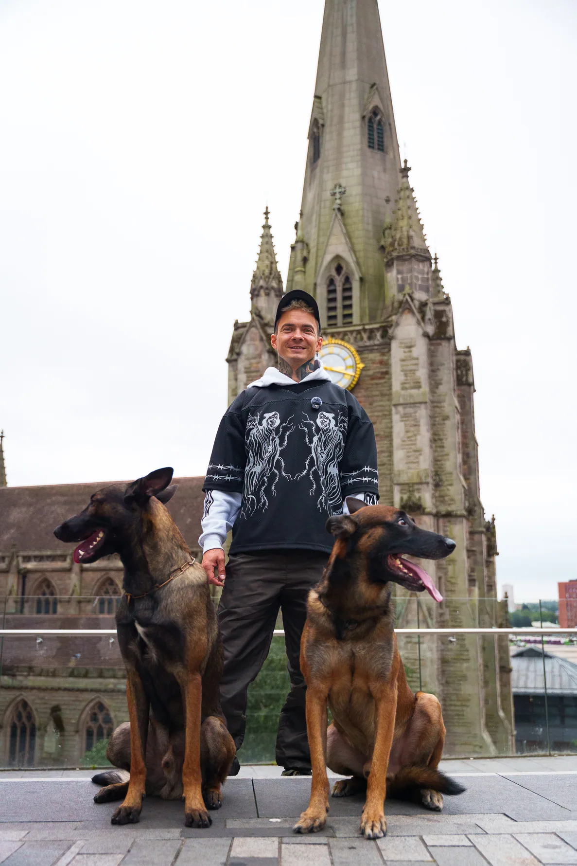 Andrejus standing with two dogs beside a historic Birmingham church