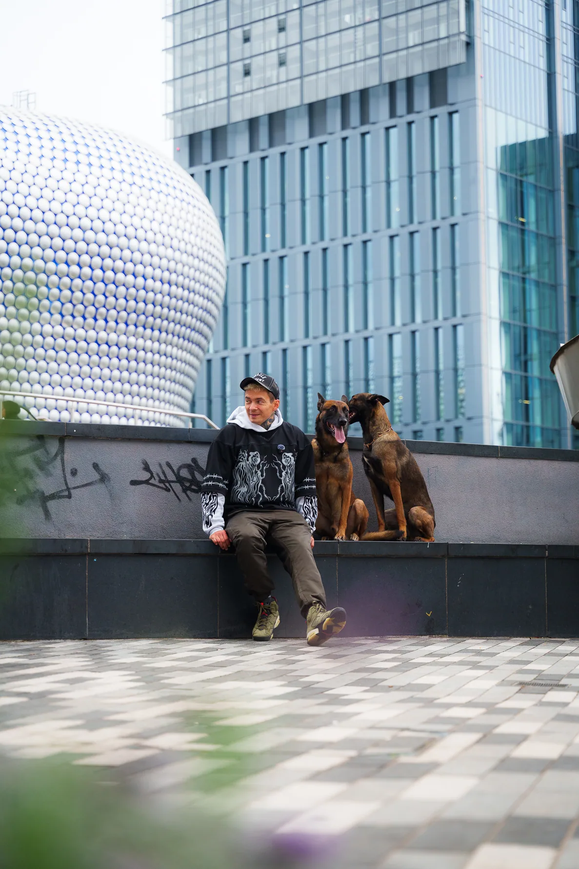 Andrejus and two dogs sitting with a city skyline in the background