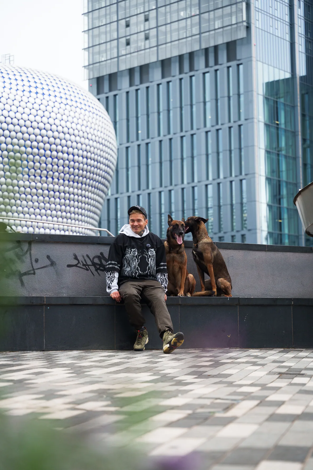 Urban training photo showing Andrejus with his dogs beside modern buildings