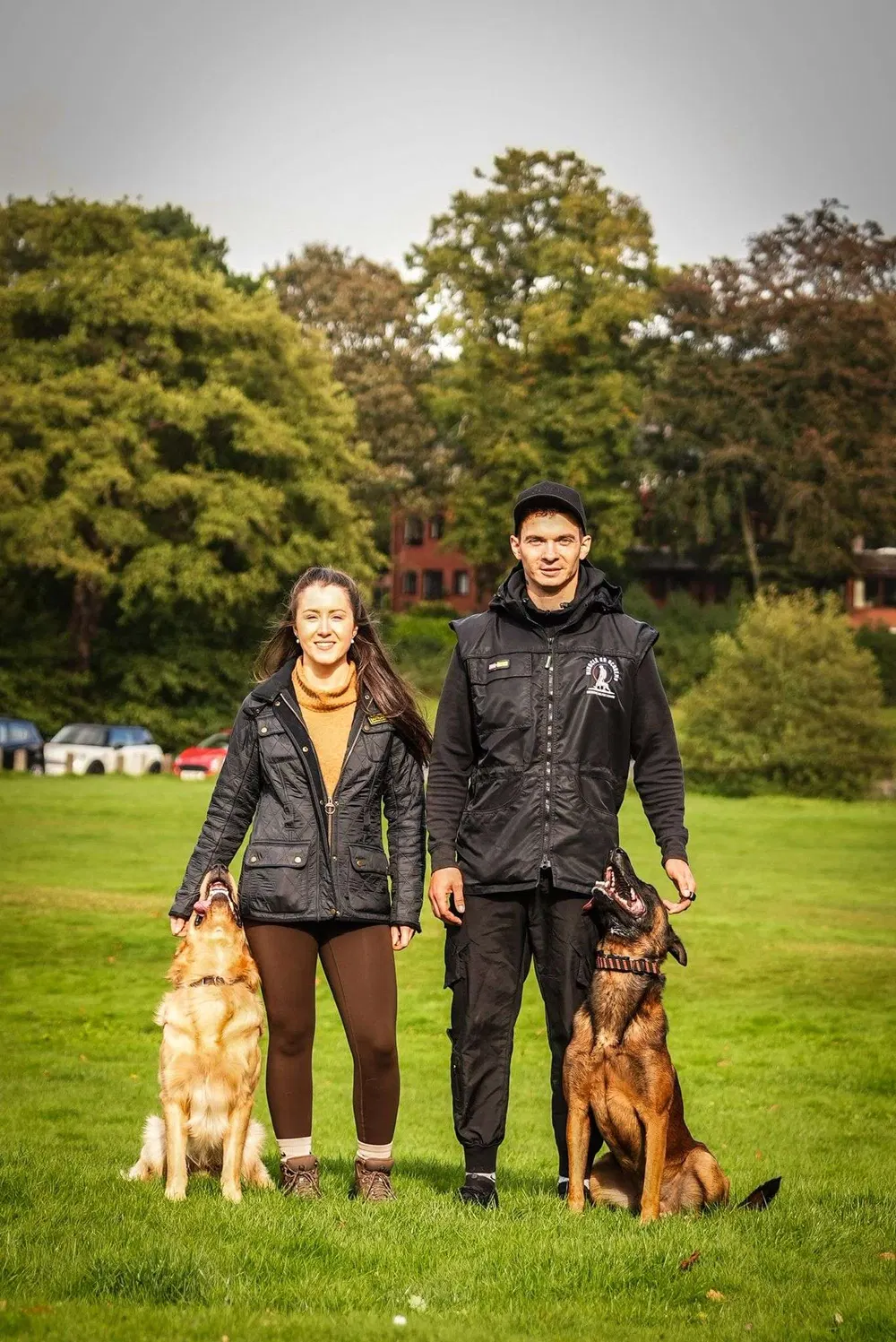Dog handlers posing with trained dogs after an outdoor session